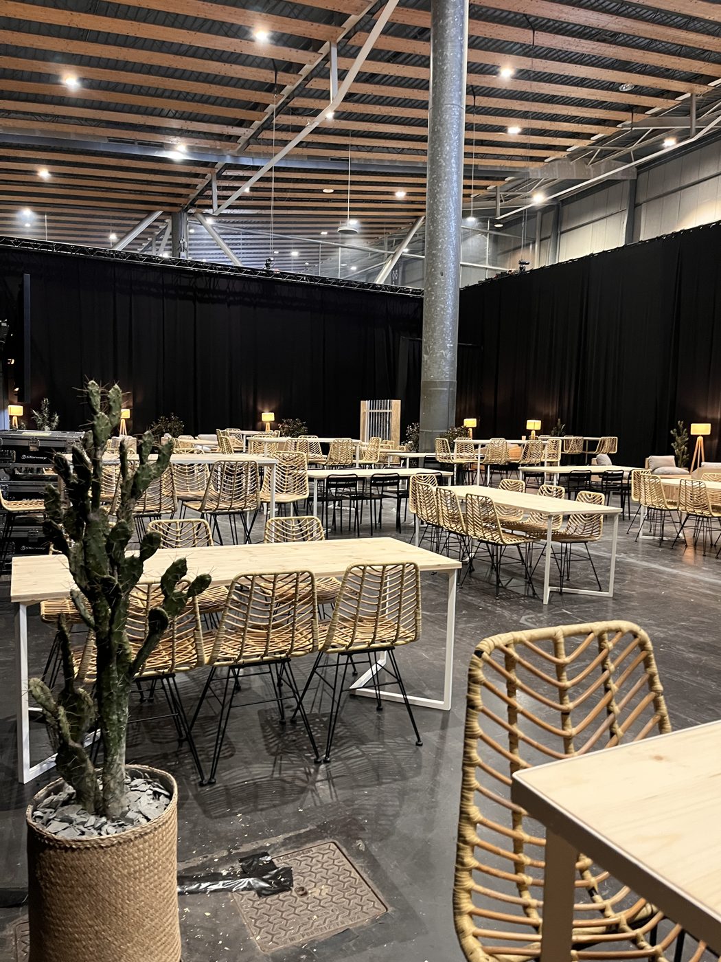 Tables en bois et chaises en rotin dressées dans un hall de Lille Grand Palais