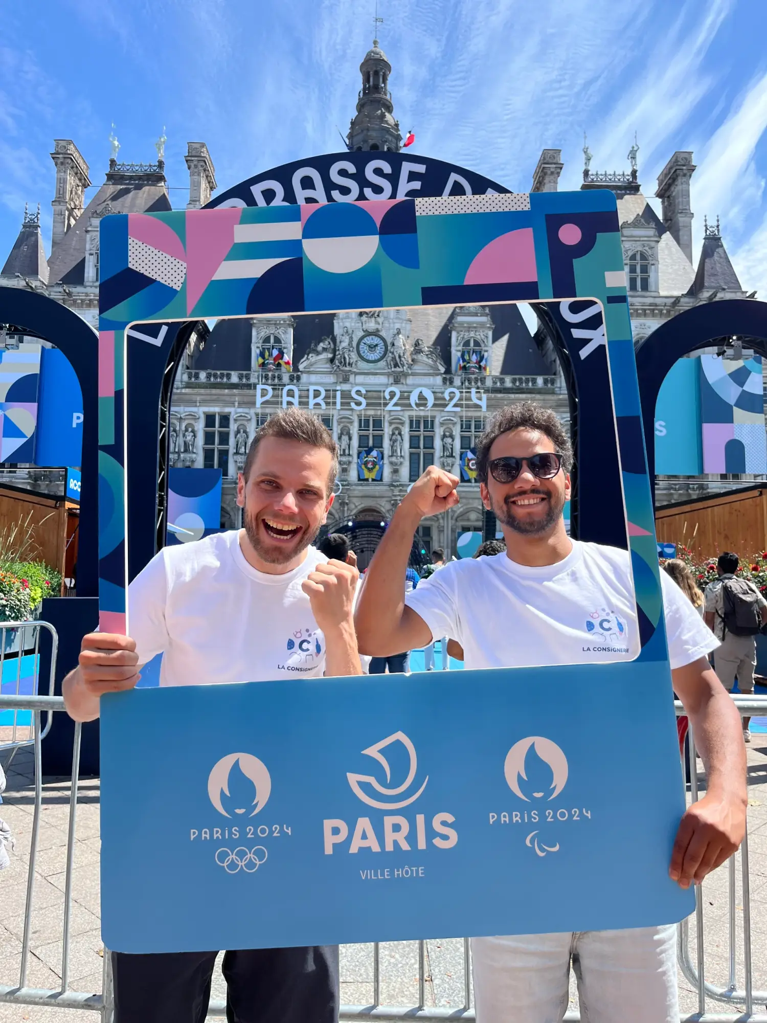 Deux personnes posent dans un cadre Paris 2024 devant l'Hôtel de Ville de Paris