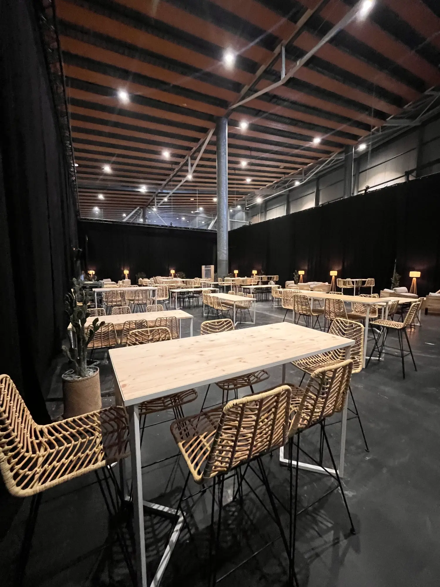 Tables hautes et tabourets en rotin installés dans un grand hall
