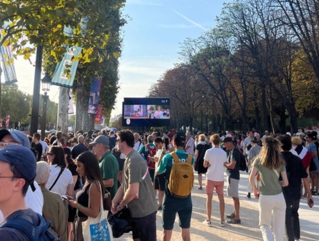 Spectateurs sur l'avenue devant un écran géant