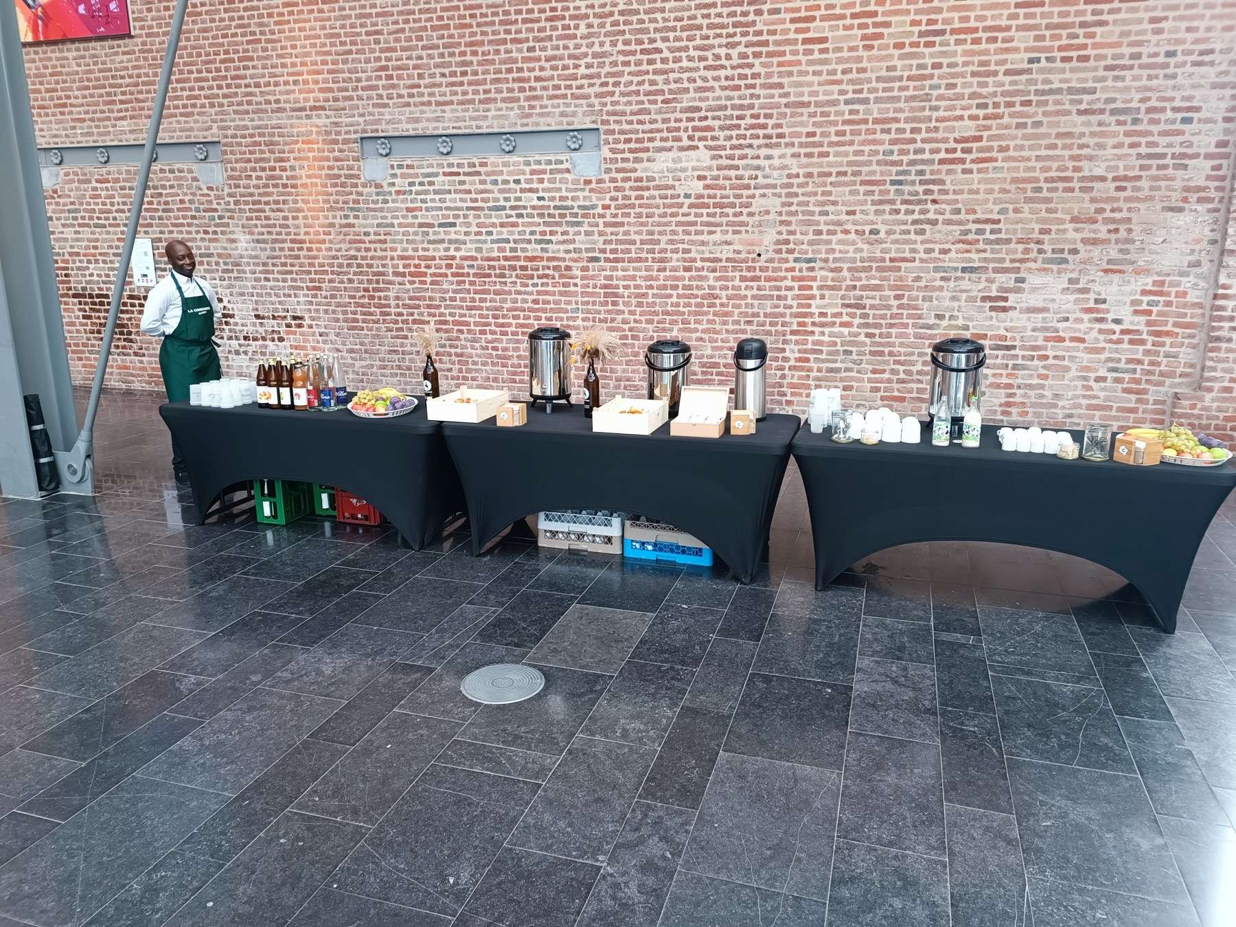 Buffet Brio dressé sur trois tables noires devant le mur de briques de l'atrium d'EuraTechnologies