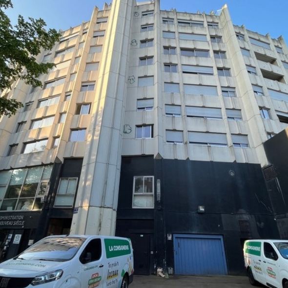 Façade du Nouveau Siècle et camionnettes de livraison